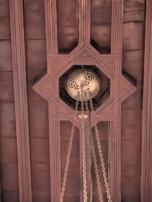 Plafond de bois sculpté du patio, une lanterne suspendue à des chaînes